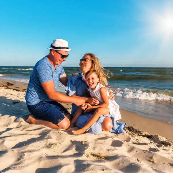 Famille souriante jouant sur une plage ensoleillée