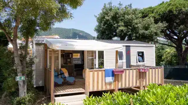 Mobil-home avec terrasse en bois entouré d’arbres
