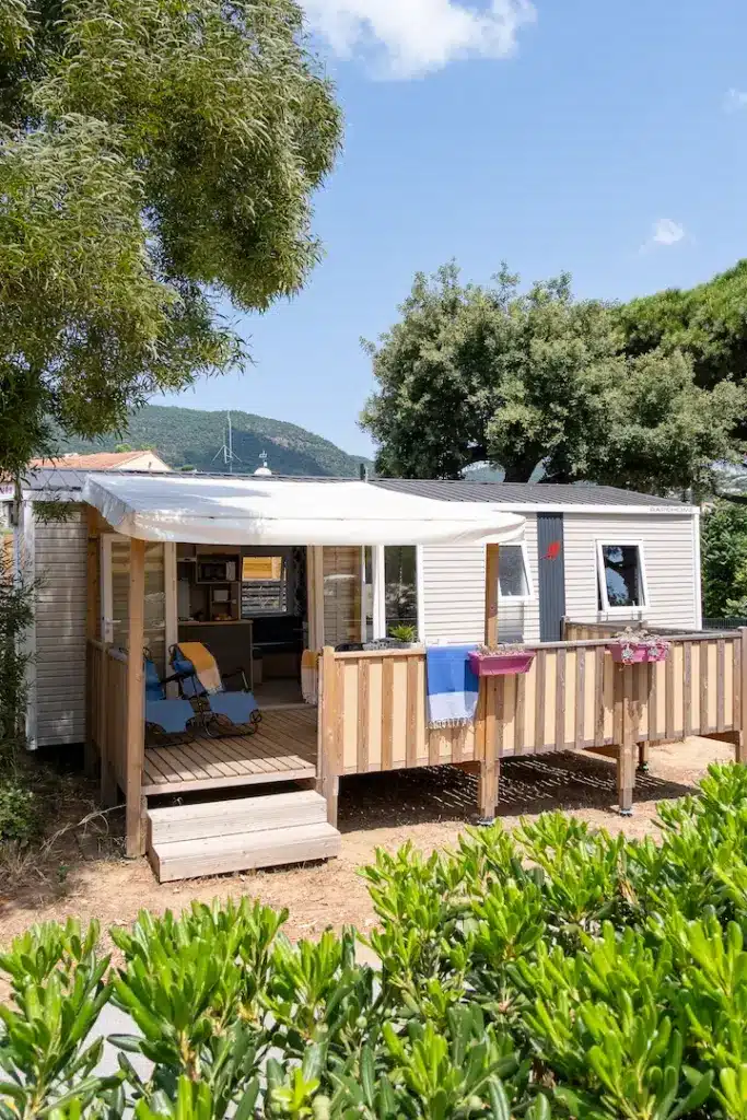 Mobil-home avec terrasse en bois entouré de verdure