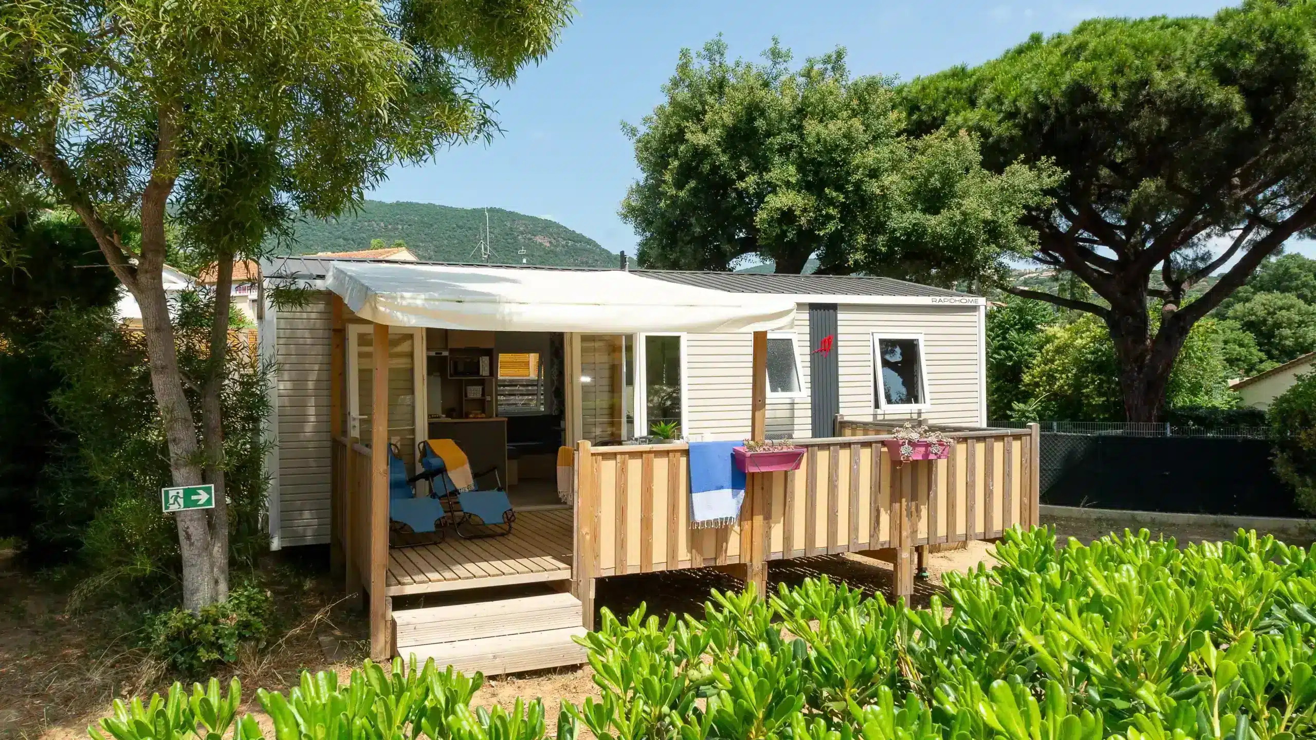 Mobil-home avec terrasse en bois entouré d’arbres