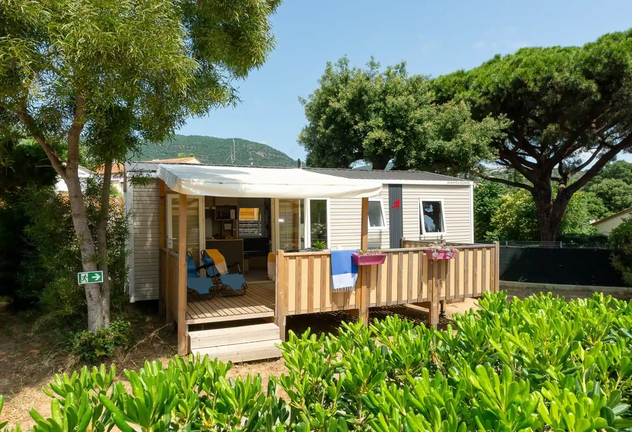Mobil-home avec terrasse en bois entouré d’arbres