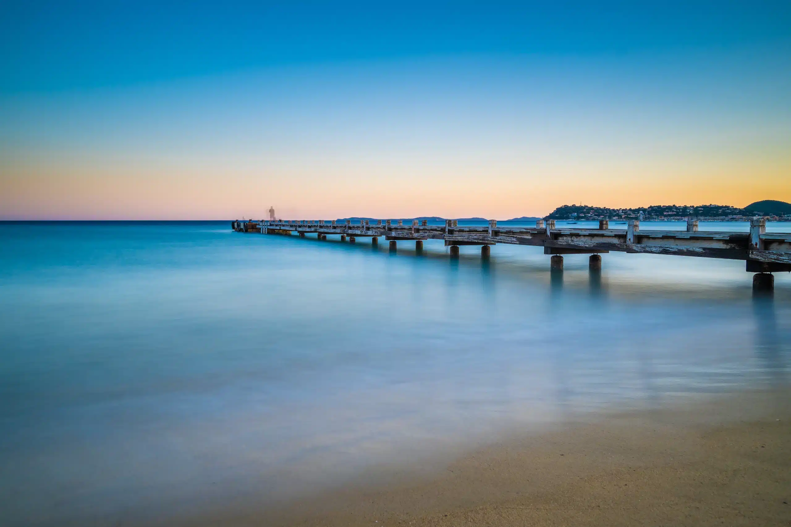 Jetée en bois sur mer calme au coucher du soleil