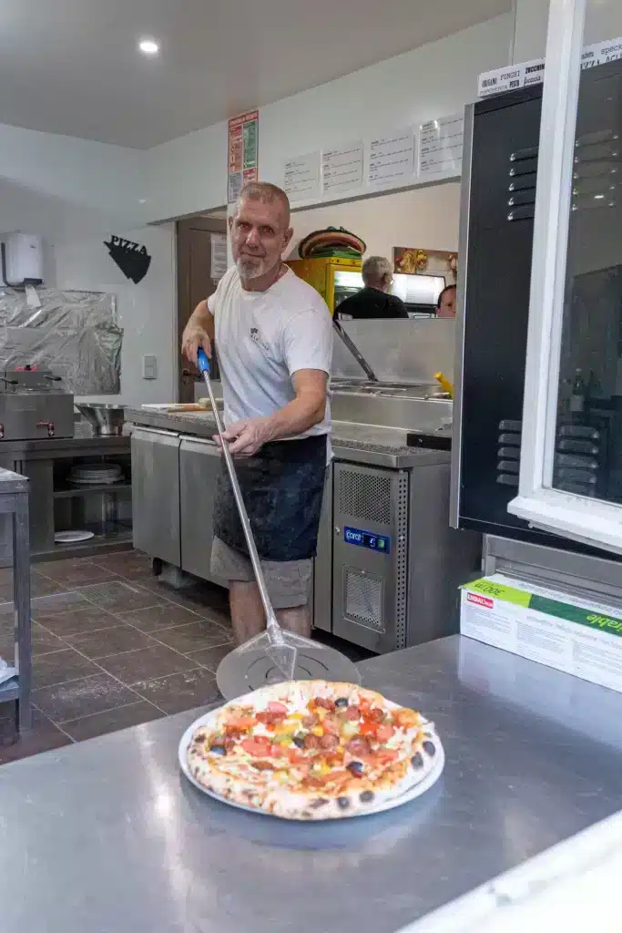 Pizzaiolo sortant une pizza dans sa cuisine