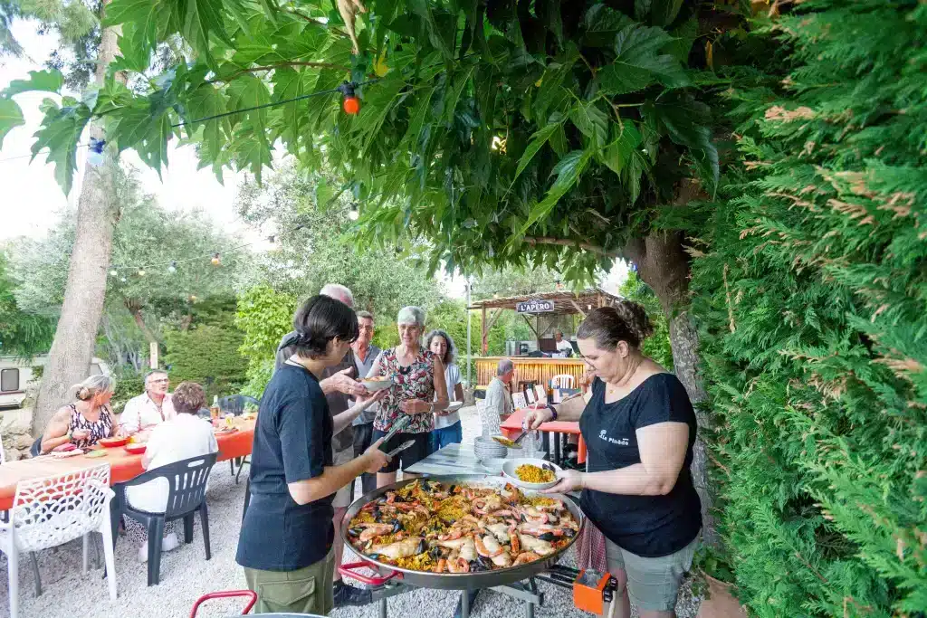 Personnes se servant une paella dans un jardin