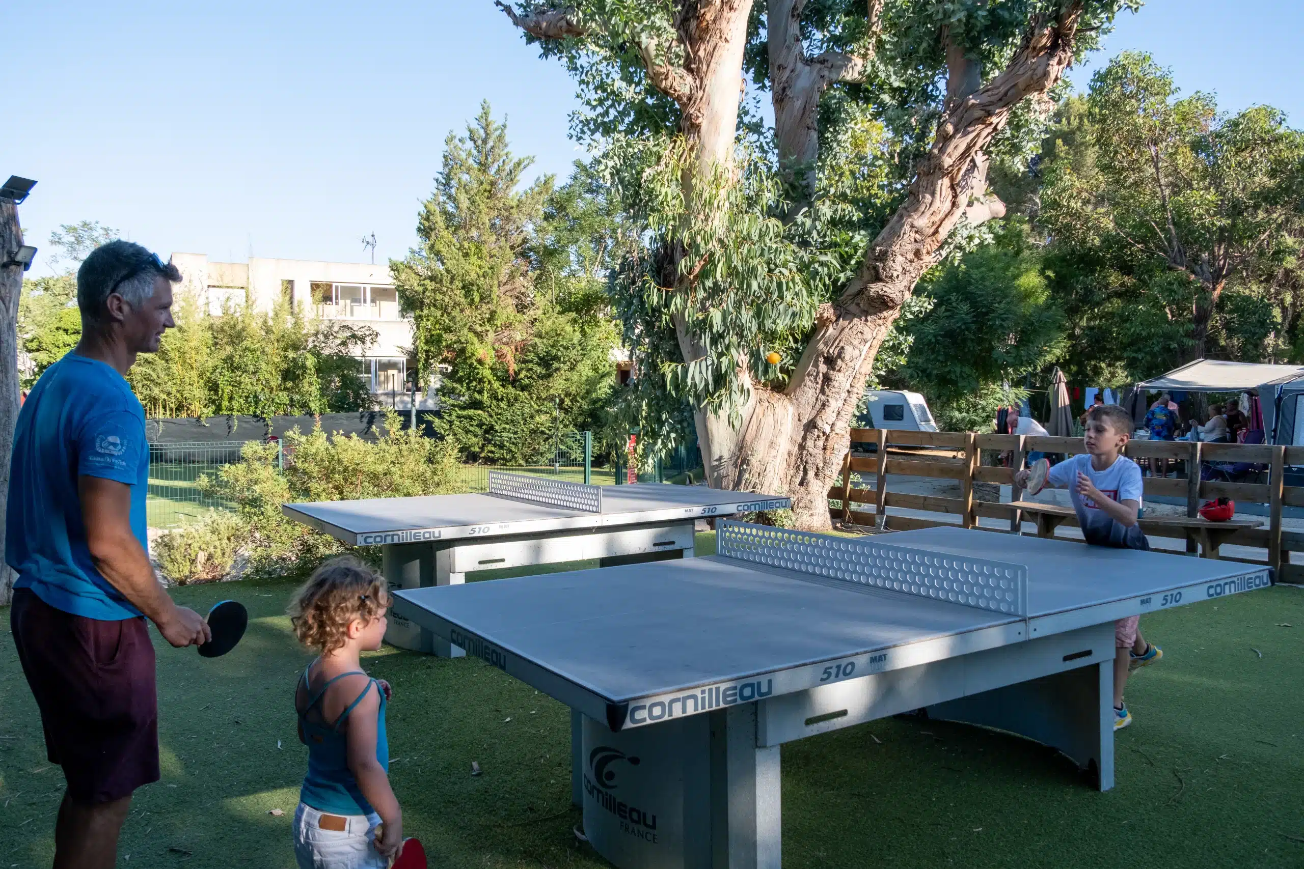 Famille jouant au ping-pong en extérieur