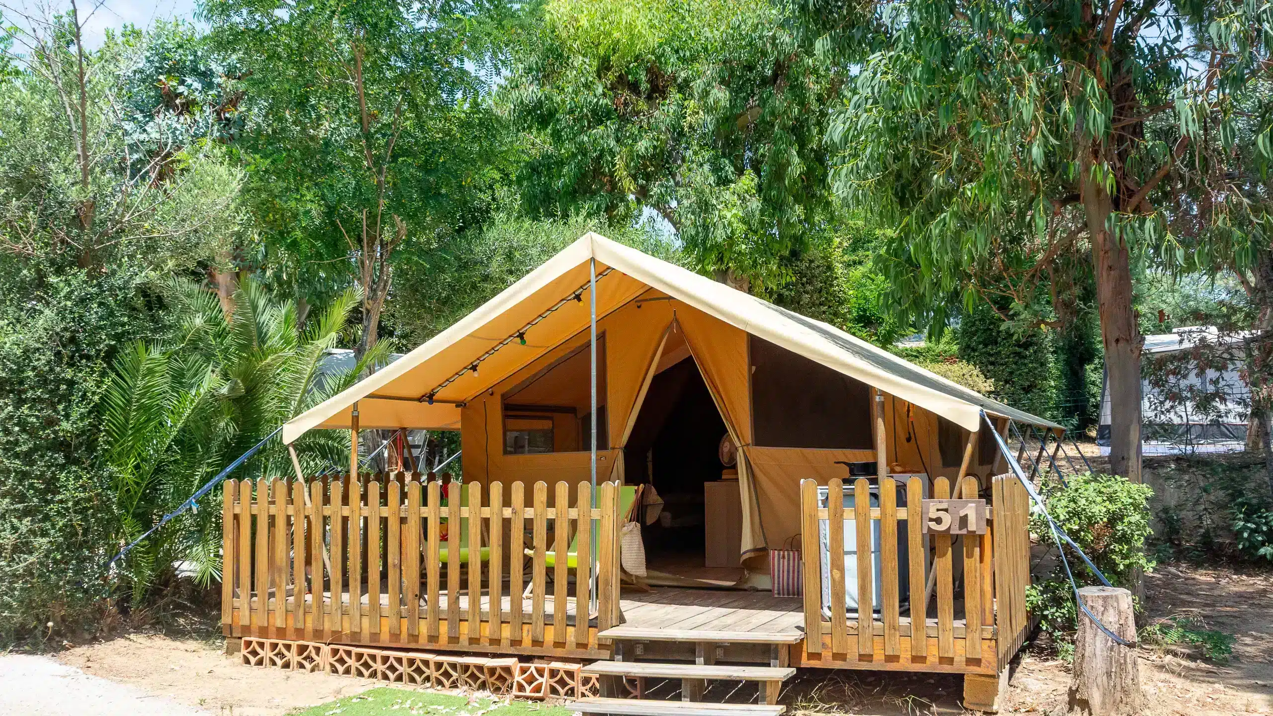 Tente safari avec terrasse en bois entourée d’arbres