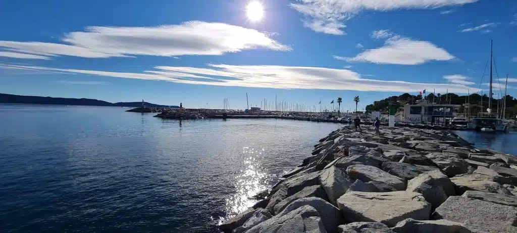 Port ensoleillé avec digue rocheuse et bateaux